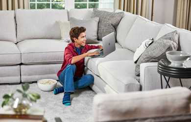 teen boy sits on clean carpet and uses computer