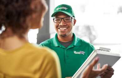 Carpet cleaning company employee greets homeowner at door